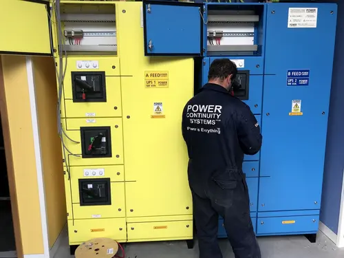 Power continuity engineer maintaining a yellow ups and blue ups